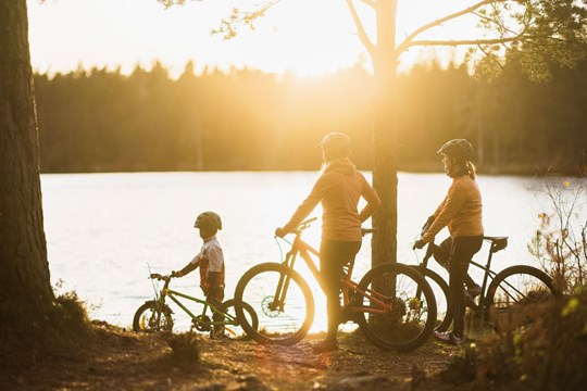 En barnfamilj på cyklar spanar ut över en sjö.