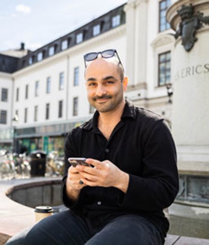 man i somrig stadsmiljö med mobiltelefon