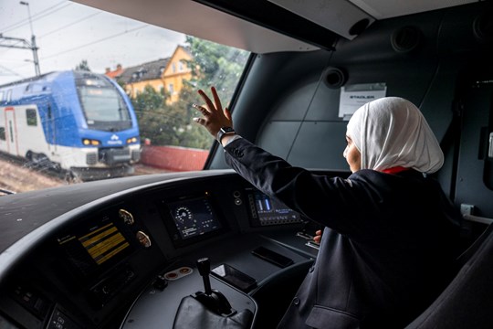 Tågförare vinkar till mötande tåg genom fönstret